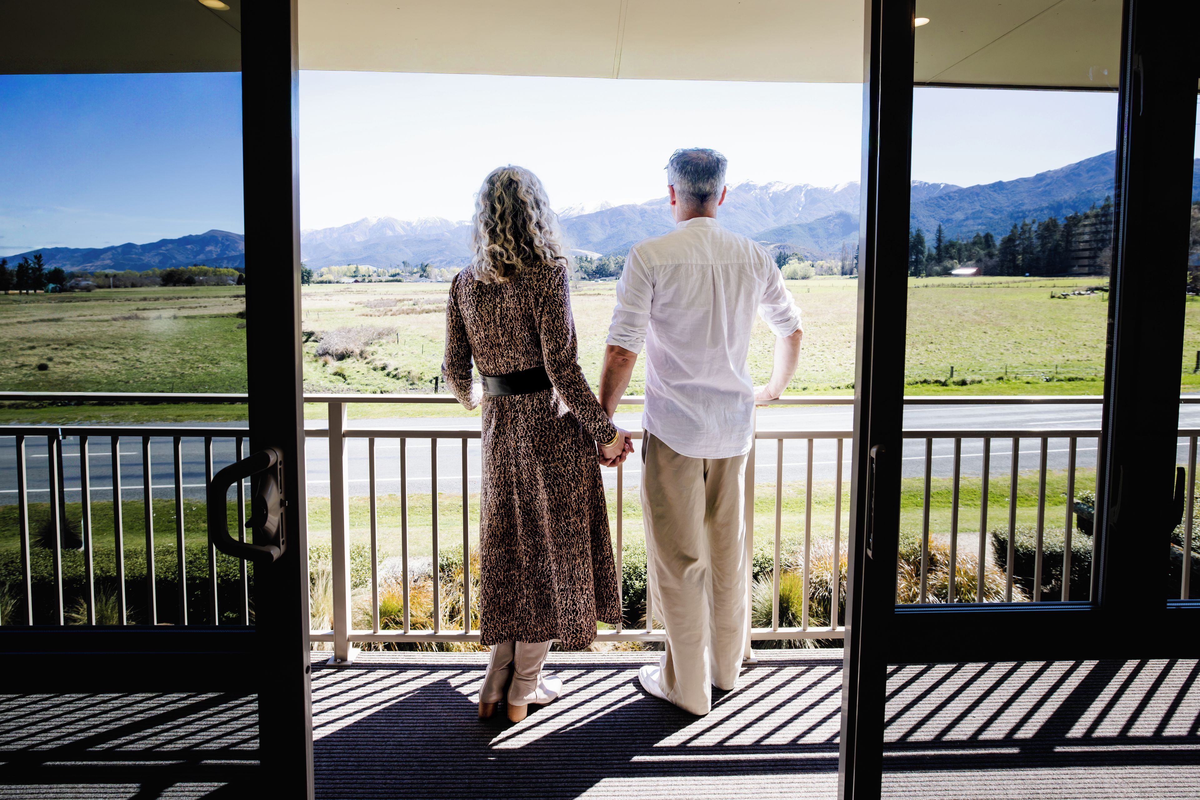 A couple standing on a balcony with a view of a mountainous landscape.