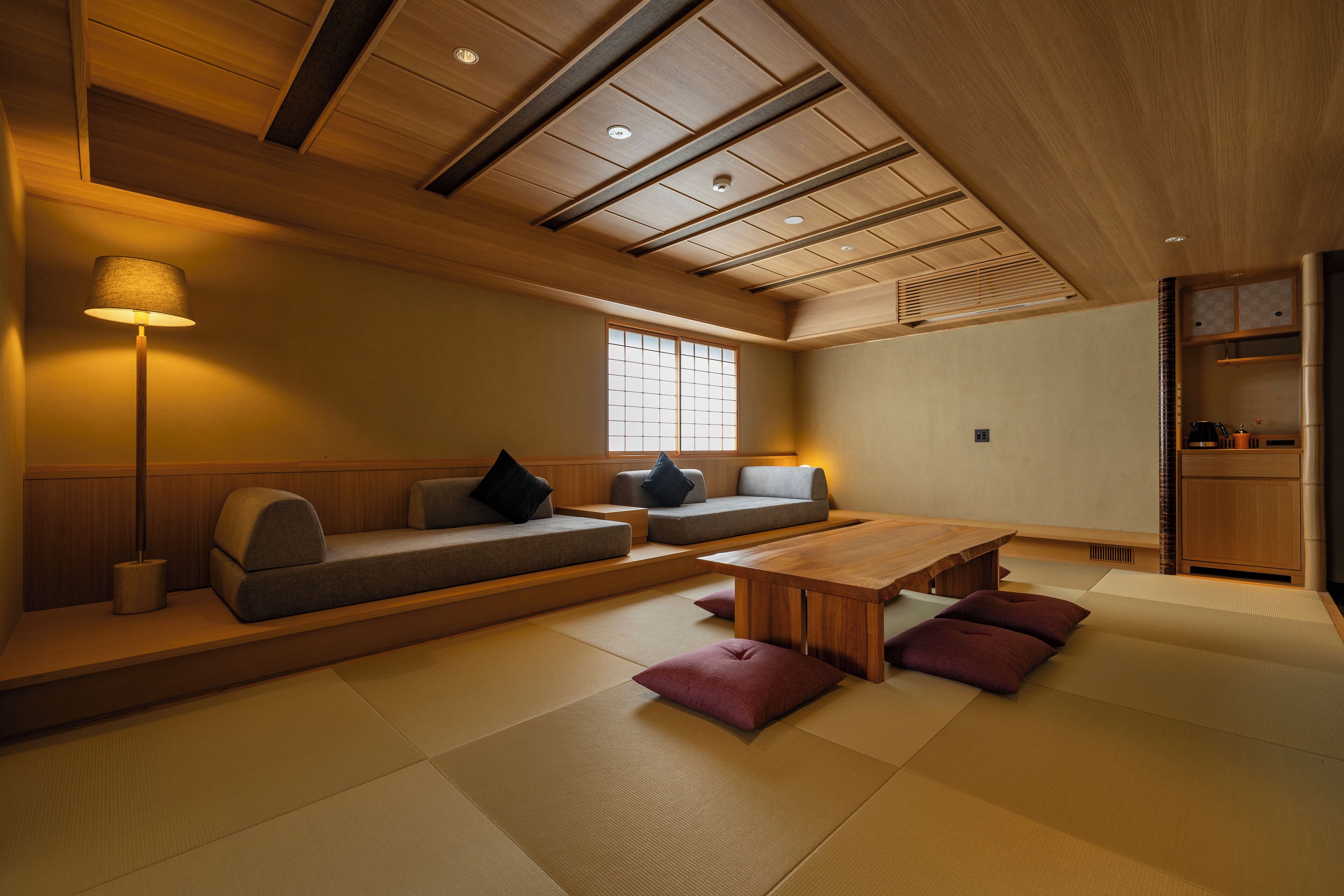 A traditional Japanese-style room with tatami flooring, low wooden furniture, and a ceiling with recessed lighting.