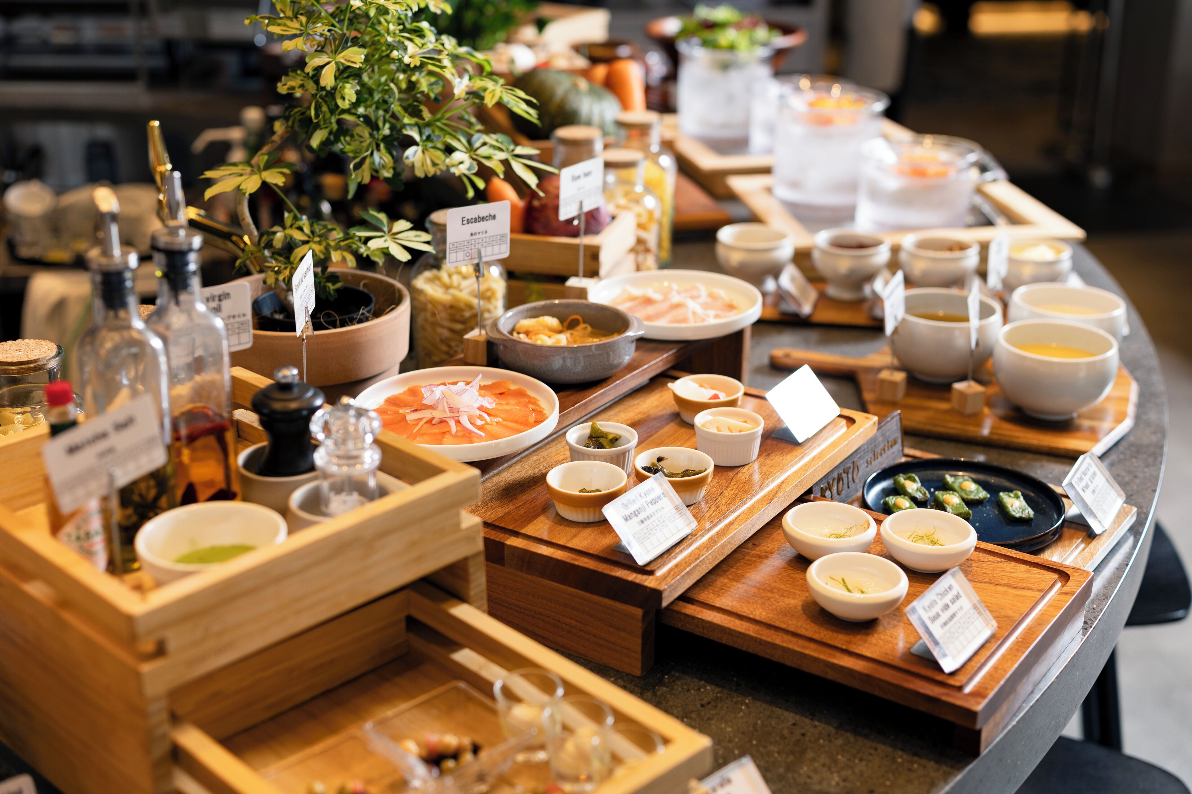 A buffet with various dishes and condiments, including a plant and a wooden tray.