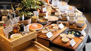 A buffet with various dishes and condiments, including a plant and a wooden tray.