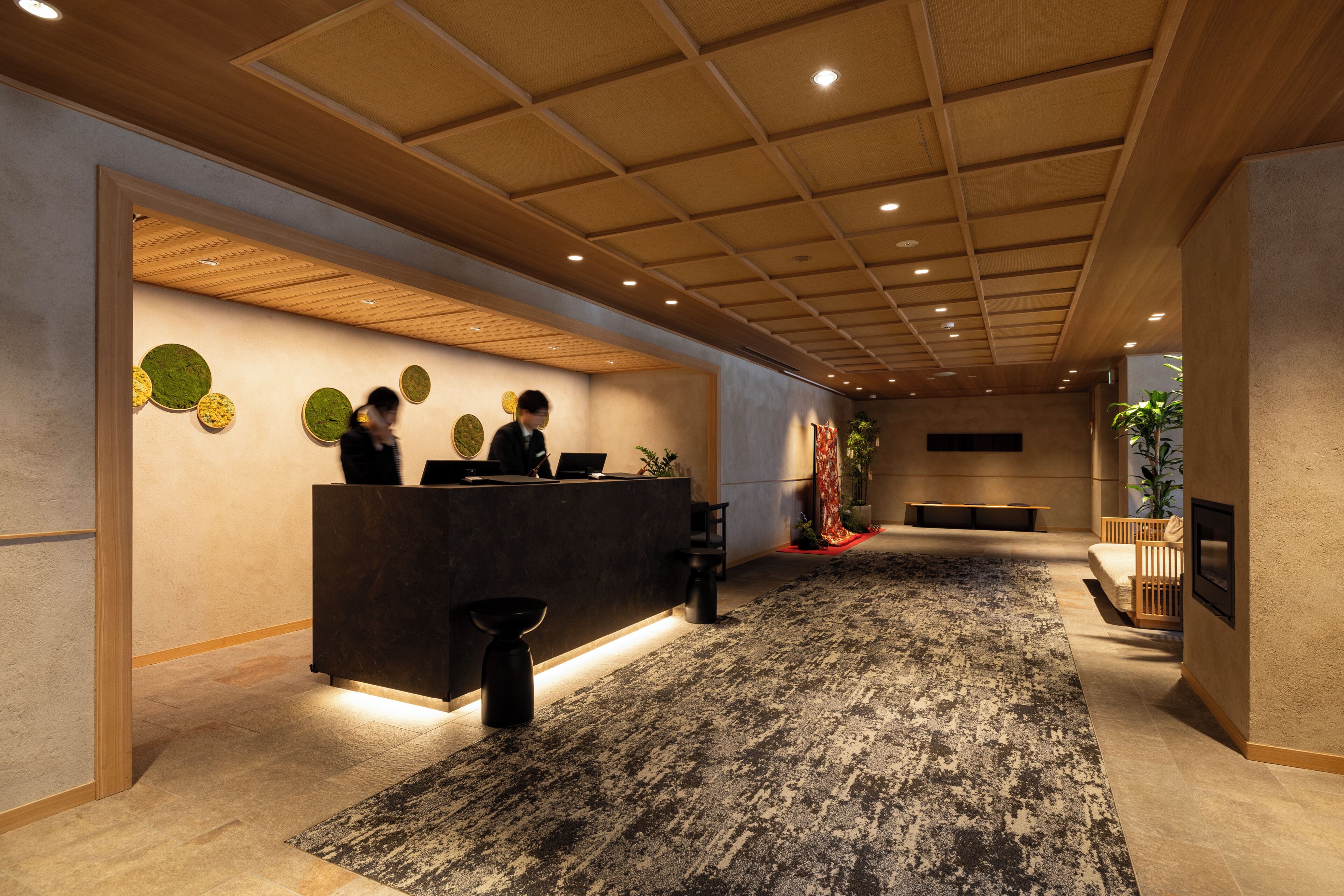 A reception area with a wooden reception desk, a patterned carpet, and a wall with circular decorations.