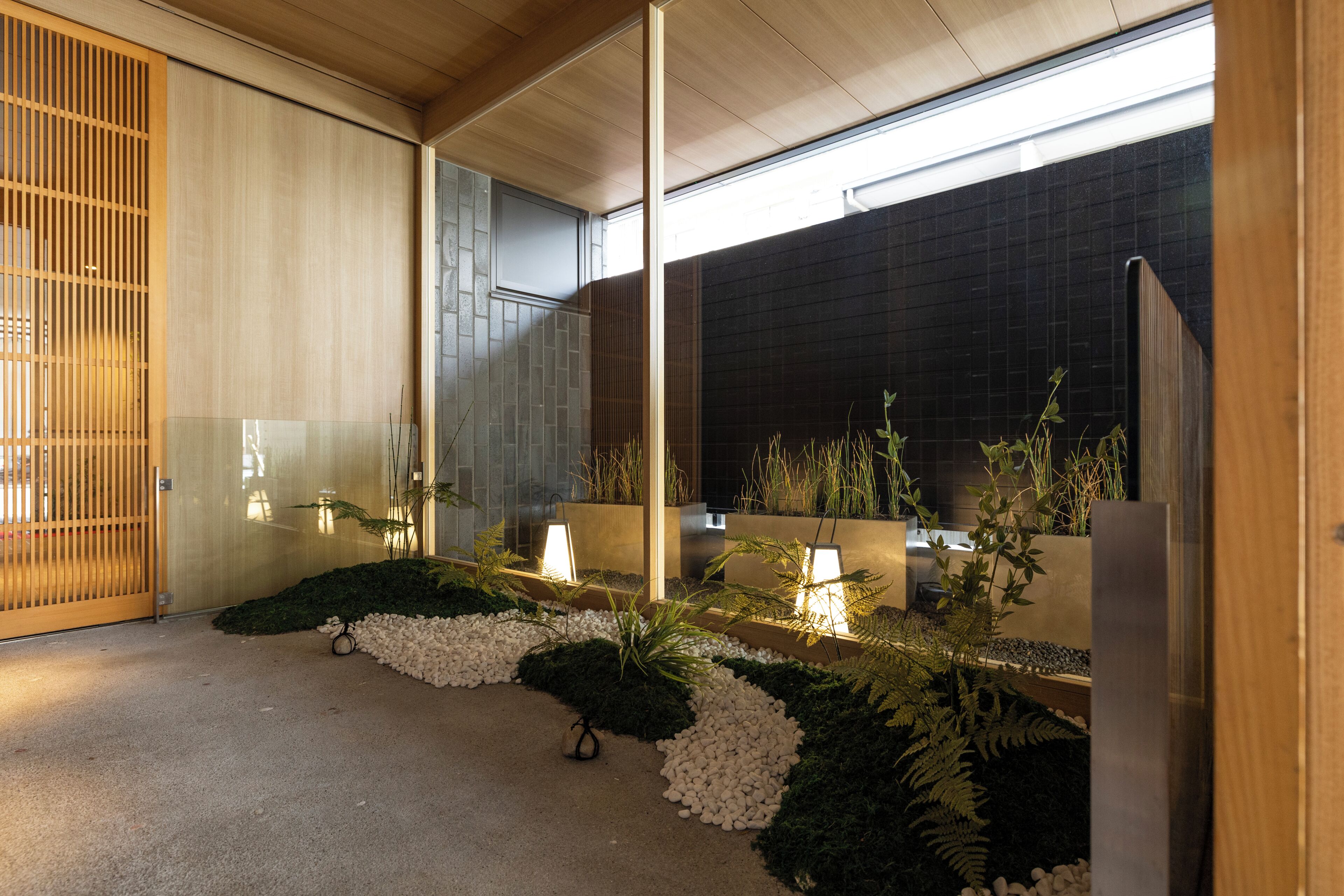 Un intérieur moderne avec un plafond en bois, une cloison en verre et un mur recouvert de carreaux sombres.