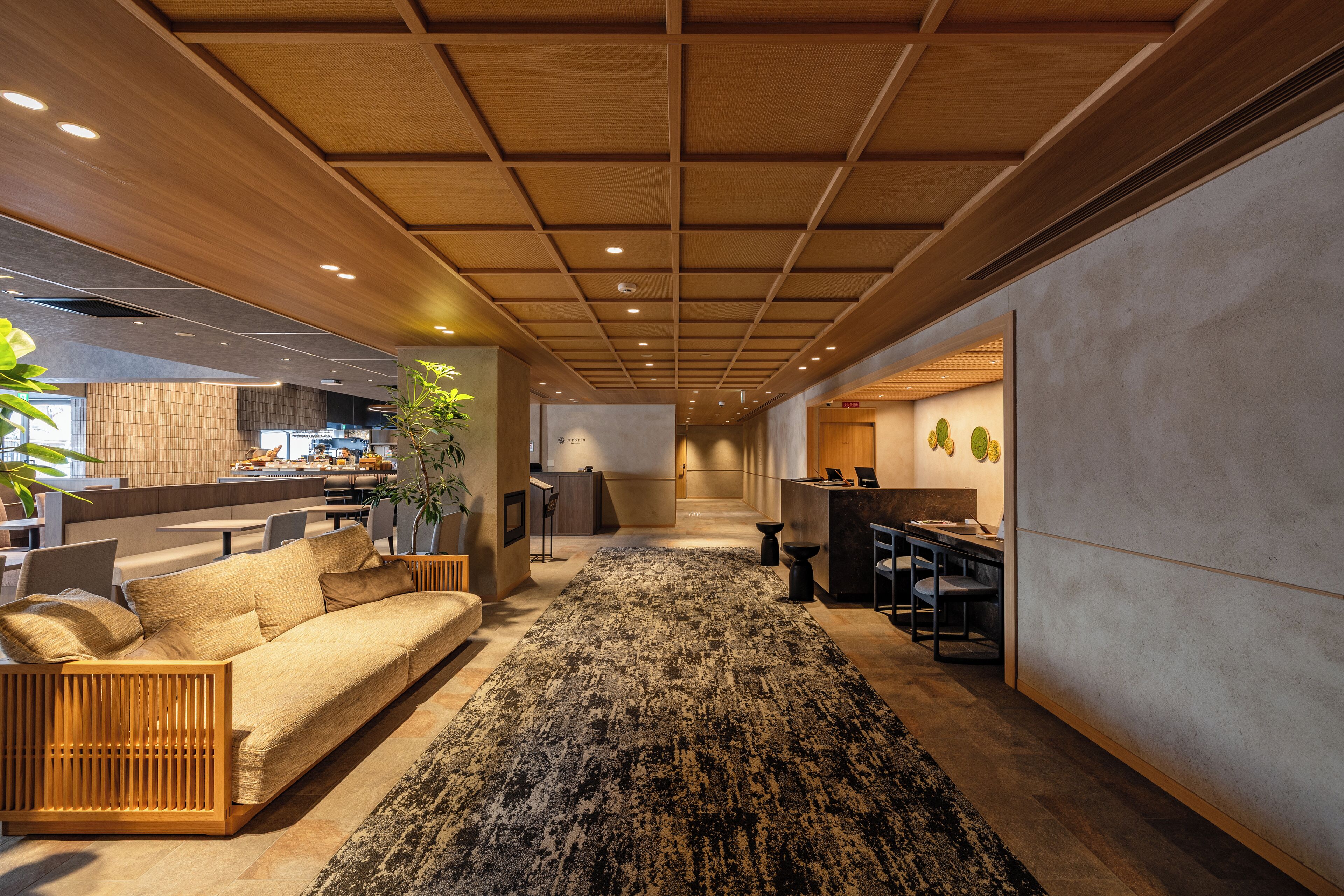 A modern interior with a wooden ceiling, a central rug, a sofa, and a dining area.