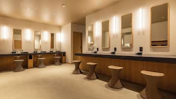 Une salle de bain moderne dotée de plusieurs lavabos, de miroirs et de tabourets en osier.