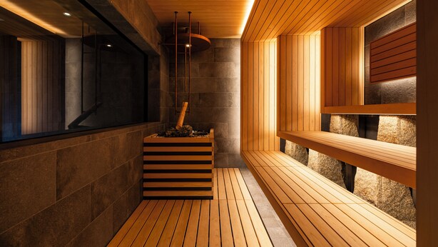 A sauna with wooden benches, a stone wall, and a wooden ceiling.