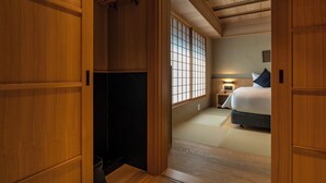 A traditional Japanese room with tatami flooring, a bed, a nightstand, and sliding doors.