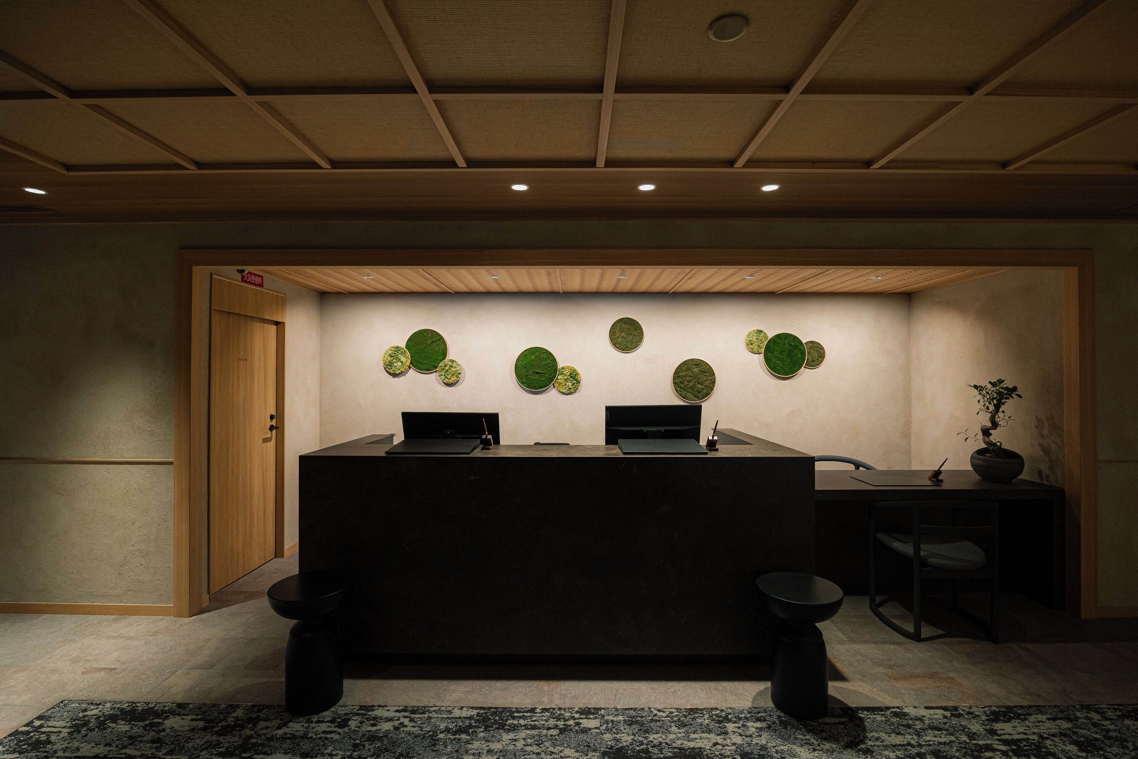 A reception desk with a dark surface, a wooden door, and a wall with circular green decorations.