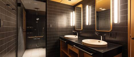 A modern bathroom with two sinks, a large mirror, and a shower area.