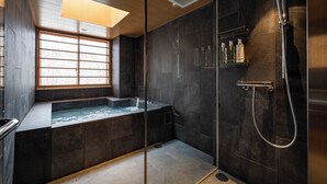 A modern bathroom with a glass-enclosed shower, a built-in bathtub, and a window providing natural light.