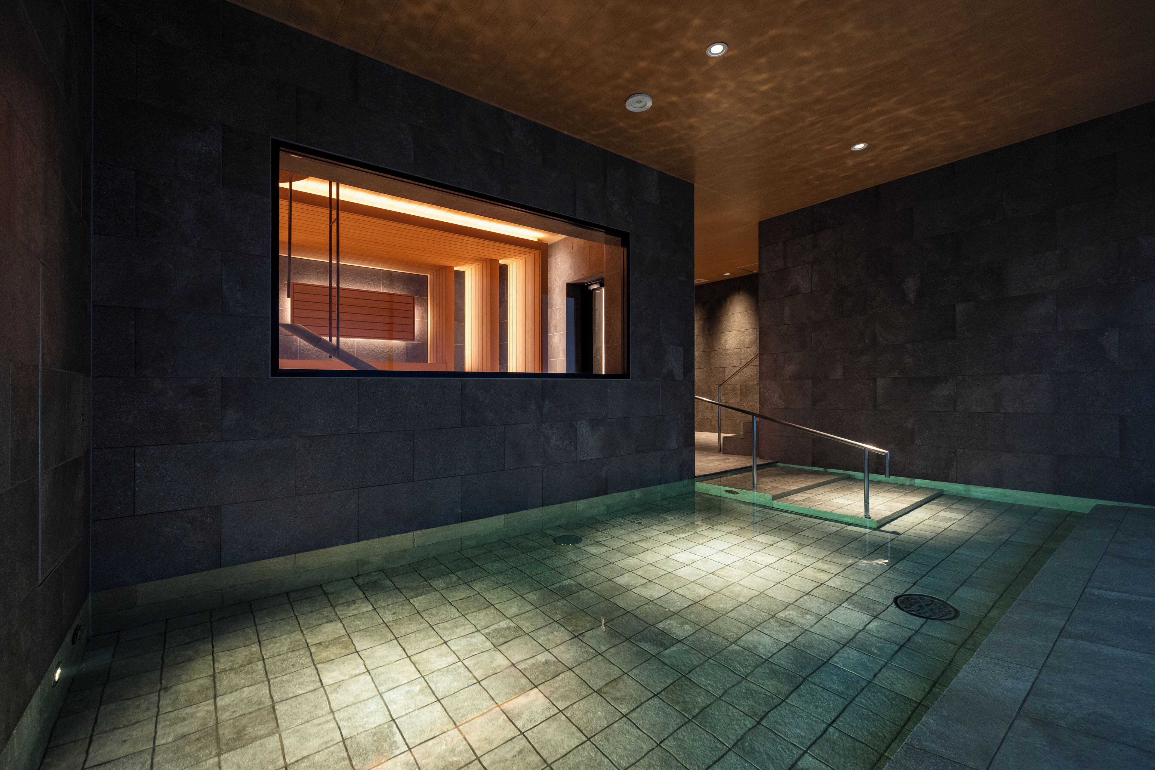 A modern interior with a large window, dark stone walls, and a tiled floor.