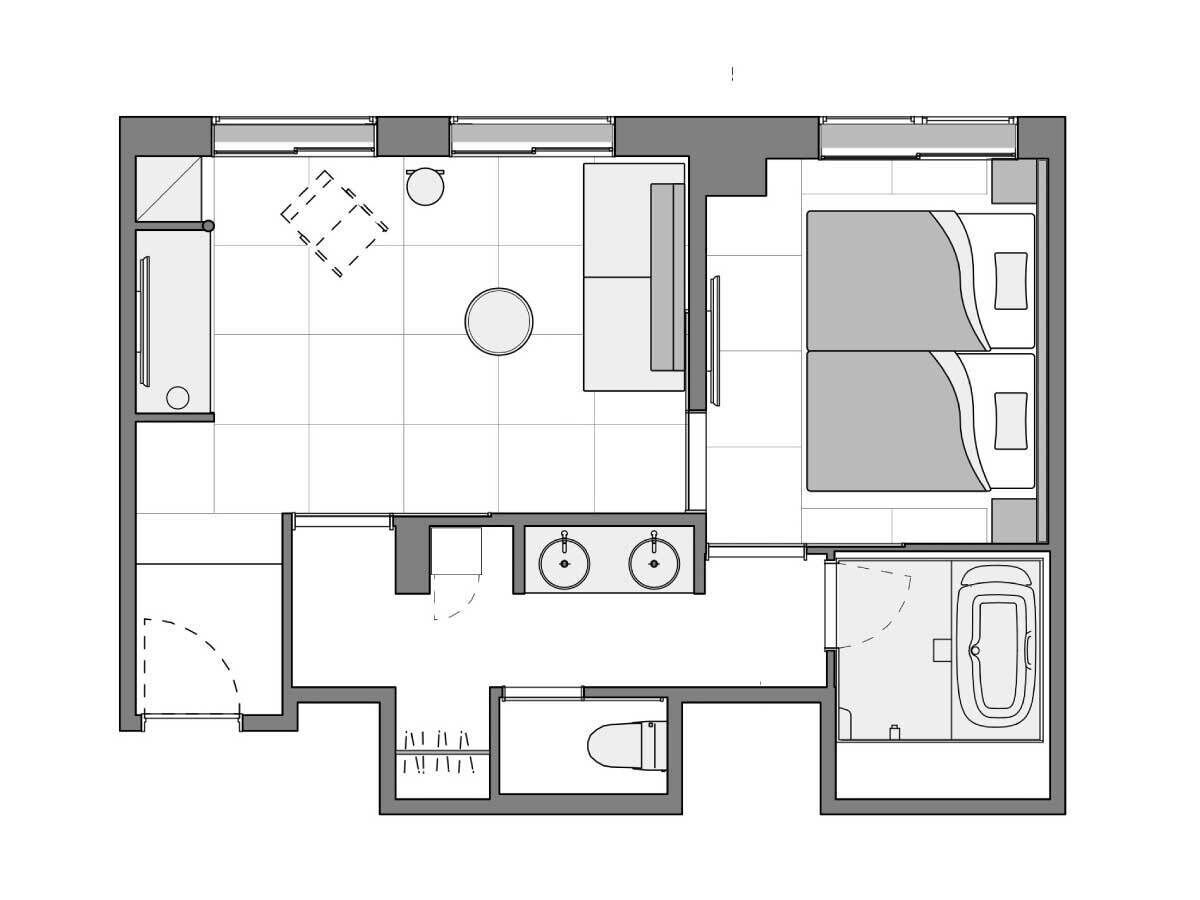 A floor plan of a hotel room with a bed, a bathroom, a small kitchen area, and a seating area.