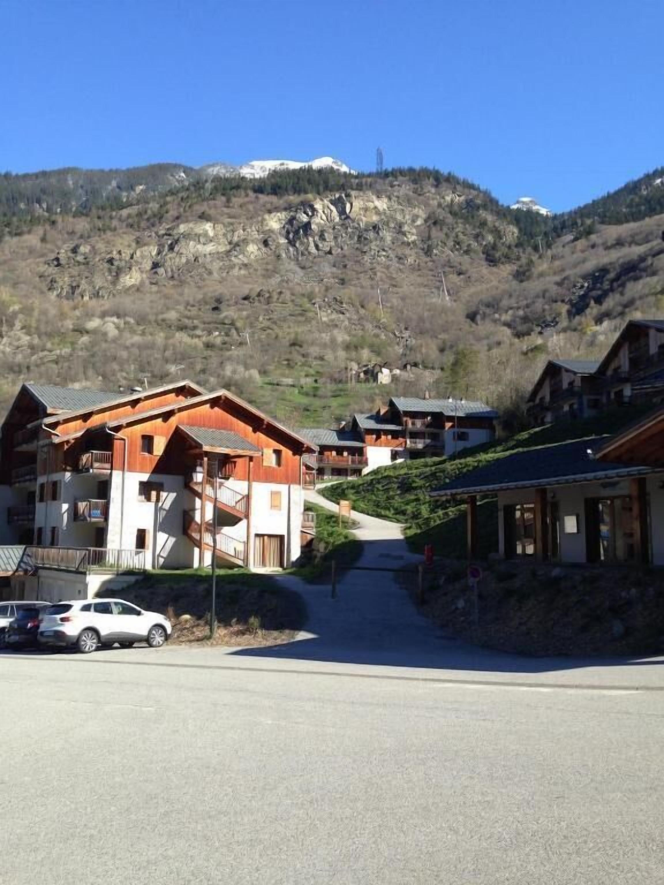 A mountain resort with wooden buildings, a parking area, and a clear view of the surrounding hills.