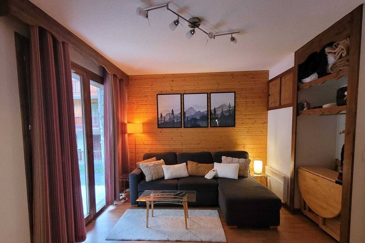 Una sala de estar acogedora con una pared de madera, un sofá, una mesa de centro y una estantería.