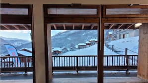 Ein Holzelement-Fenster mit Blick auf eine verschneite Berglandschaft und Gebäude.