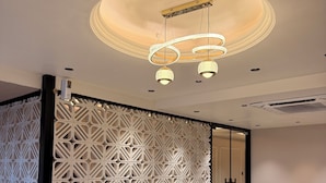 A modern interior with a geometric wall design, a ceiling light fixture, and a tiled floor. - Hotel Presidency (Surat)