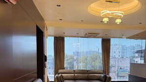 A modern hotel lobby with leather sofas, a large window offering a city view, and a contemporary chandelier. - Hotel Presidency (Surat)