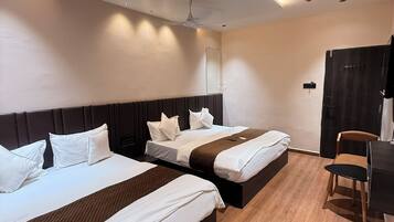 Habitación de hotel con dos camas, un escritorio, una silla, un ventilador de techo e iluminación empotrada.