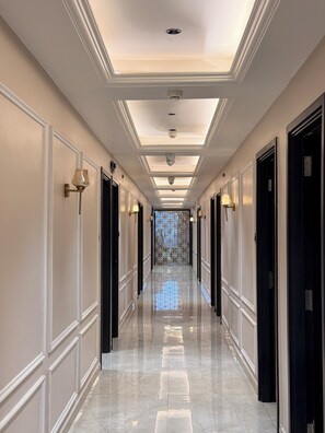Corredor com piso espelhado, iluminação embutida e portas em ambos os lados.