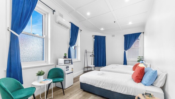 Una habitación de hotel moderna con dos camas, un escritorio, una silla y una mesita.