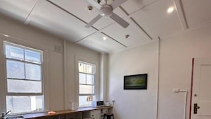 Una cocina con una mesa de madera, taburetes de bar, un ventilador de techo y una ventana.