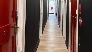 Un pasillo con paredes negras, puertas rojas y suelo de madera.