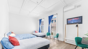 Una habitación de hotel moderna con dos camas, un escritorio y un televisor.