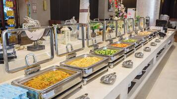 A buffet with various food options and serving utensils.