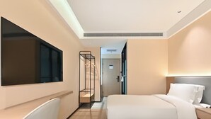 Ein modernes Hotelzimmer mit zwei Betten, einem Schreibtisch und einem Fernseher.
