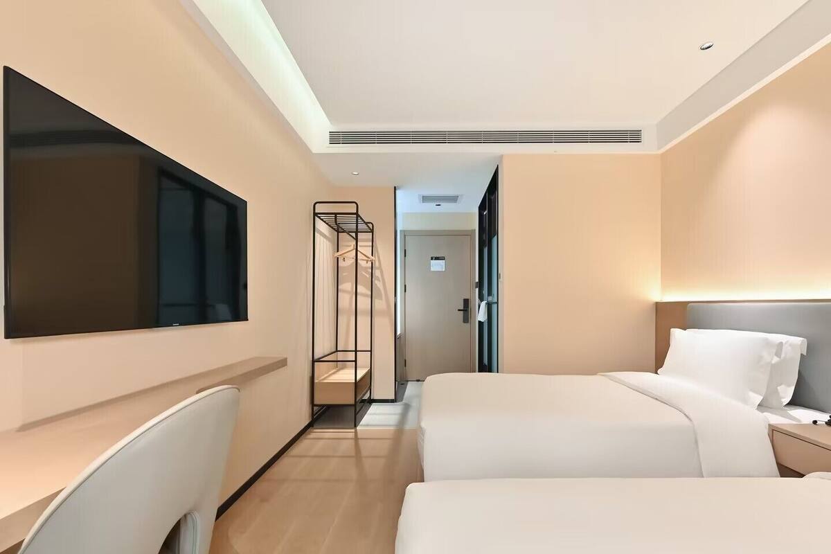 Ein modernes Hotelzimmer mit zwei Betten, einem Schreibtisch und einem Fernseher.