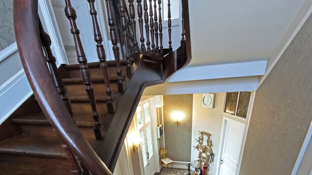 Eine Holztreppe mit Handlauf, die zu einer oberen Etage führt.