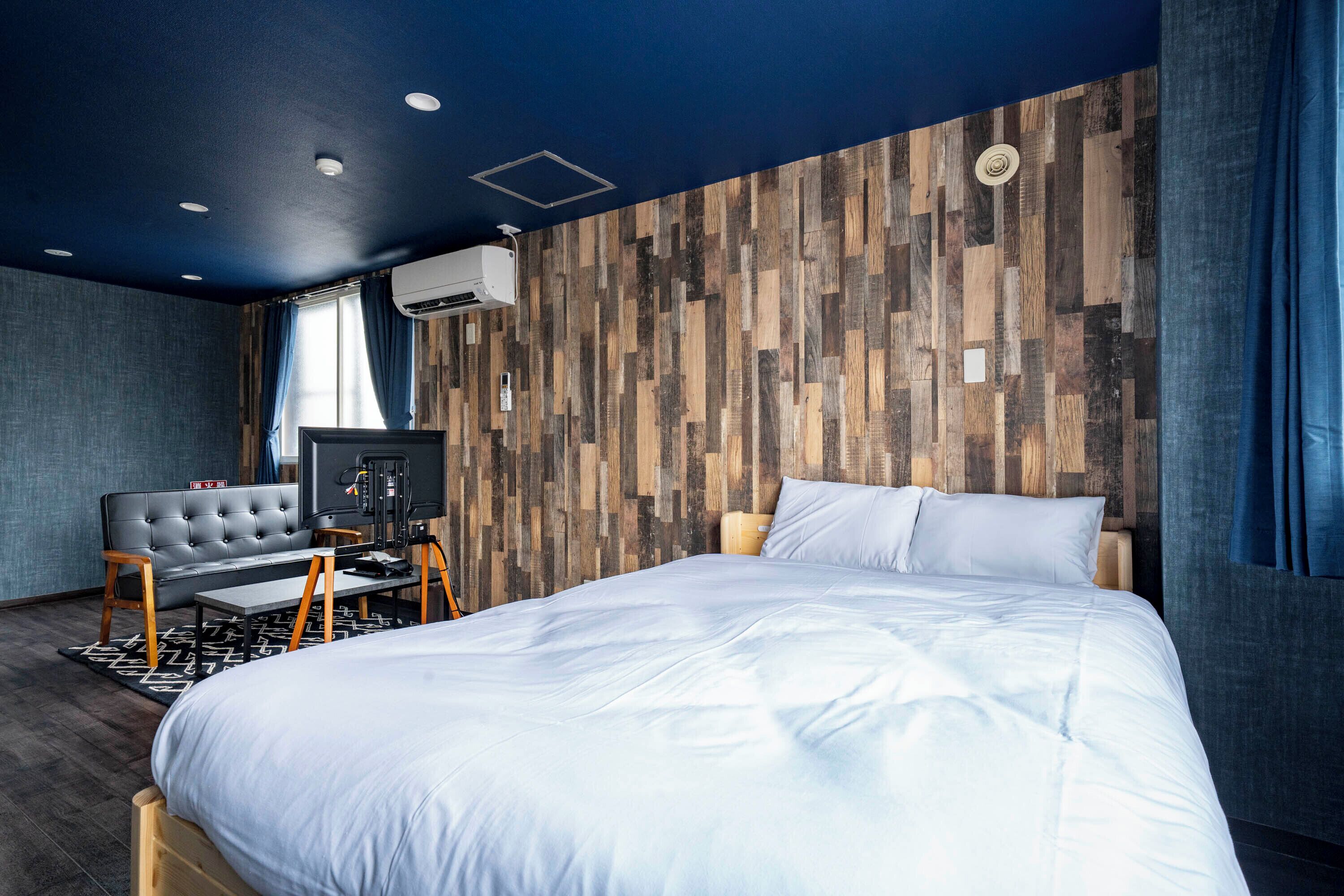 Une chambre d’hôtel moderne équipée d’un grand lit, d’un canapé, d’un bureau et d’un climatiseur fixé au mur.
