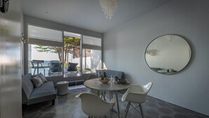 A modern dining area with a round table, white chairs, and a large mirror on the wall. - Lusa Beach Studios (Banjar)