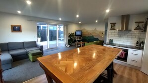 Eine moderne Küche mit Holztisch, einer Couch und einem Fernseher im Hintergrund.