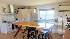 Eine moderne Küche mit einer Holzinsel, Barhocker, weißen Schränken und einem großen Fenster.
