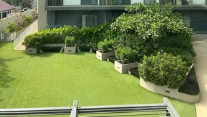 Un immeuble résidentiel à plusieurs étages, doté de balcons, d’une pelouse verdoyante et de plantes en pot.