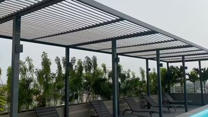 Un espace piscine aménagé sur le toit, avec un coin salon couvert et des chaises longues.
