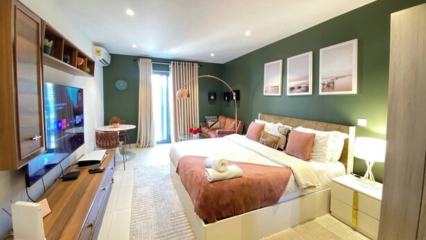 Une chambre d’hôtel moderne dotée d’un grand lit, d’un bureau avec un téléviseur à écran plat, d’un coin salon avec une table et des chaises, et d’œuvres d’art accrochées aux murs.