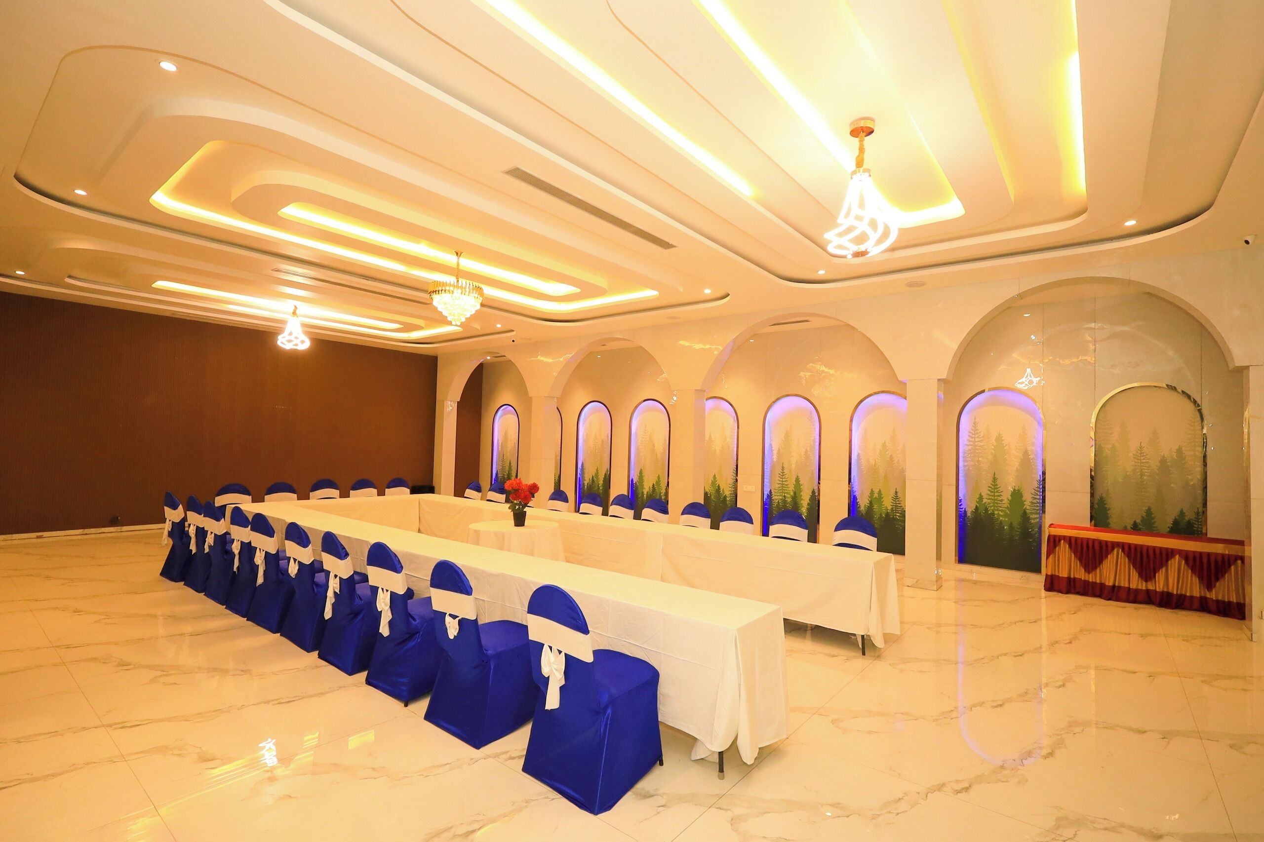A conference room with a long table, blue chairs, and a chandelier.