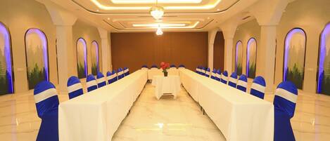 A conference room with a long table, blue chair sashes, and a chandelier.