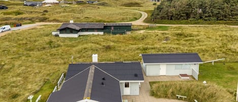 A coastal property with a large house, a smaller structure, and a pathway leading to the sea.