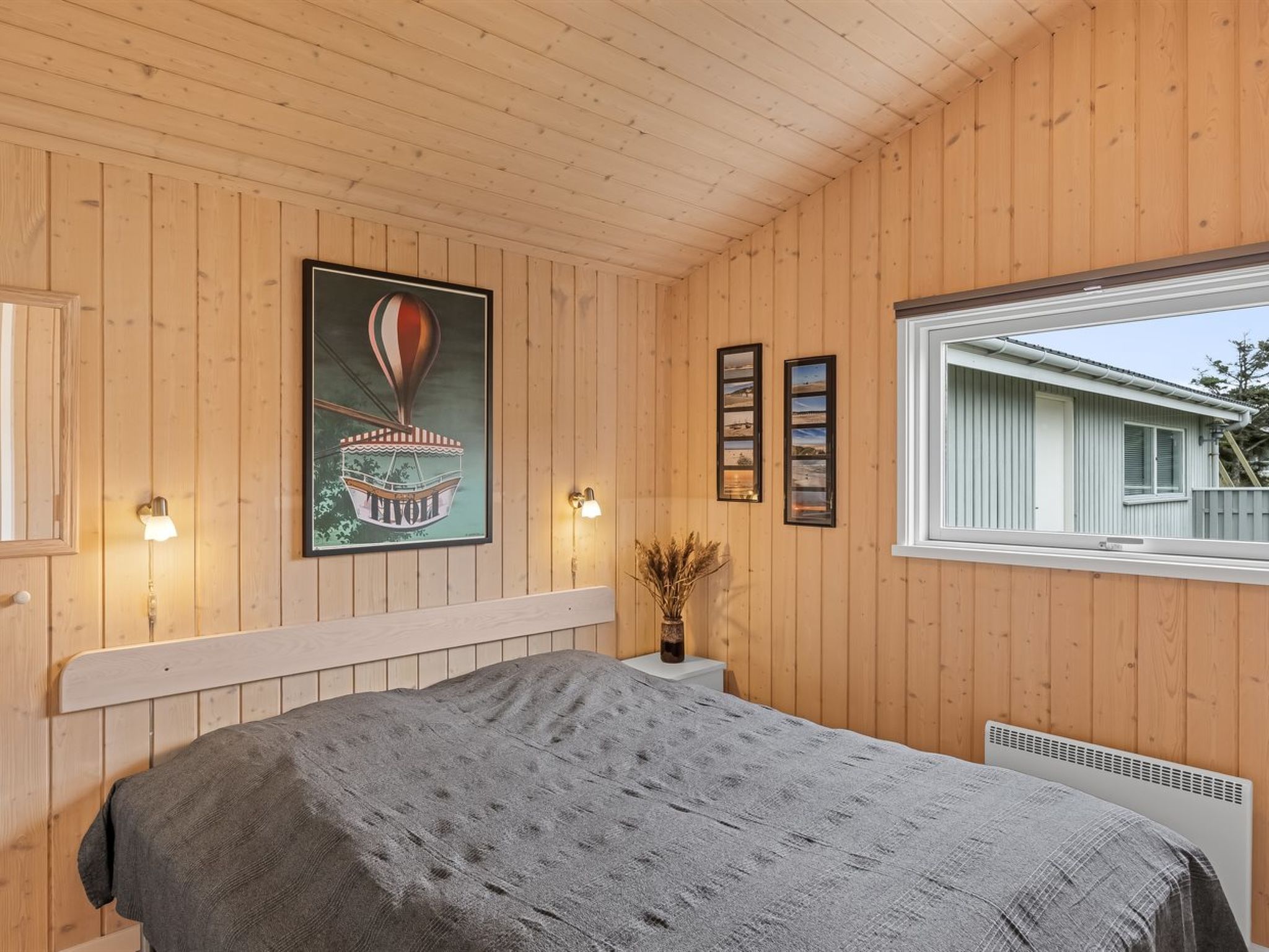 Une chambre à coucher avec un lit, des murs en bois, une fenêtre et des lampes fixées au mur.