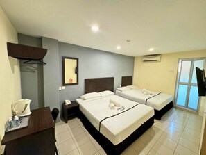 Quarto de hotel com duas camas, uma escrivaninha com telefone, cafeteira e televisão.
