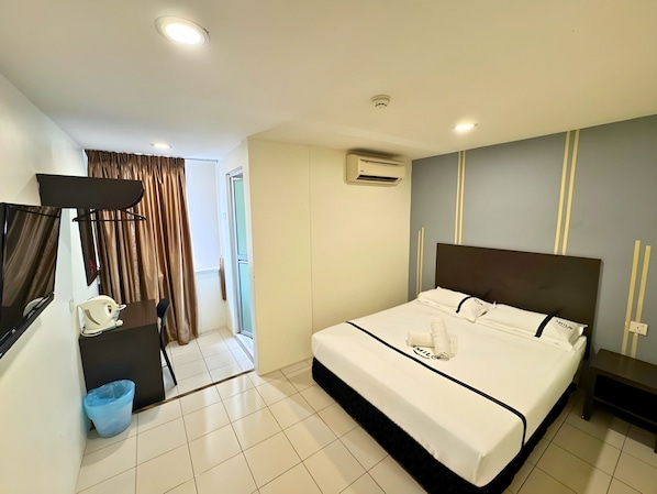A hotel room with a bed, a desk, a chair, an air conditioning unit, and a television. - Seeds Hotel Klang Meru (Klang)