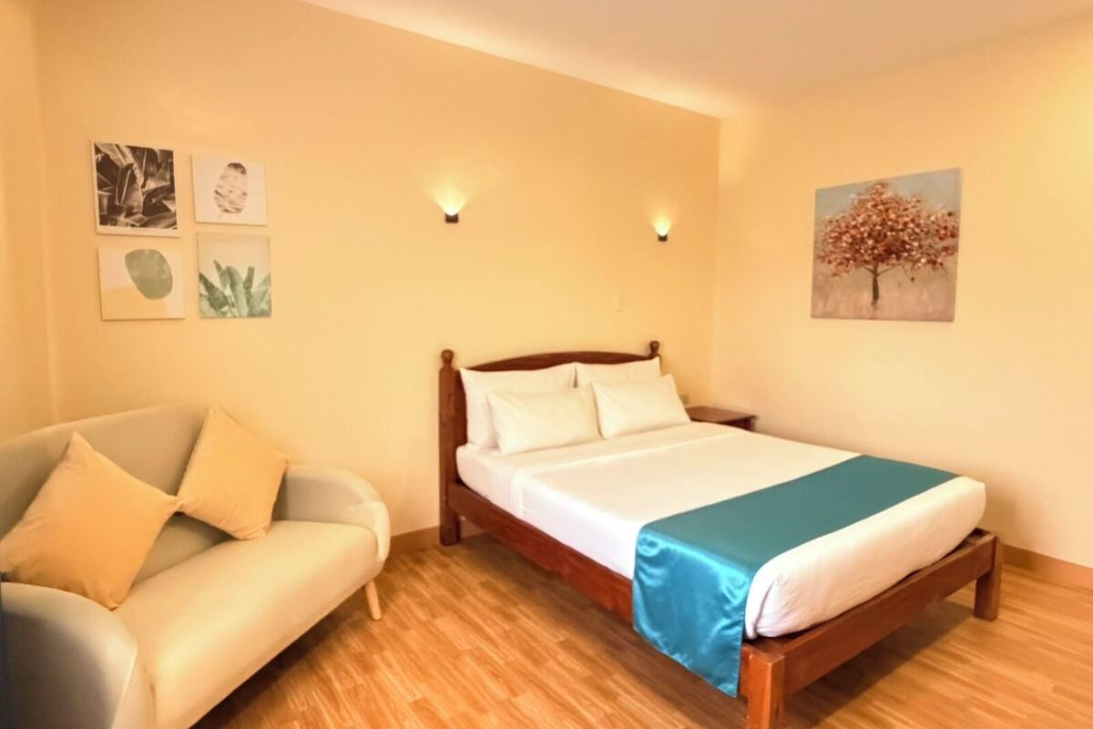 Ein Schlafzimmer mit Bett, einer Couch und Wandbildern.