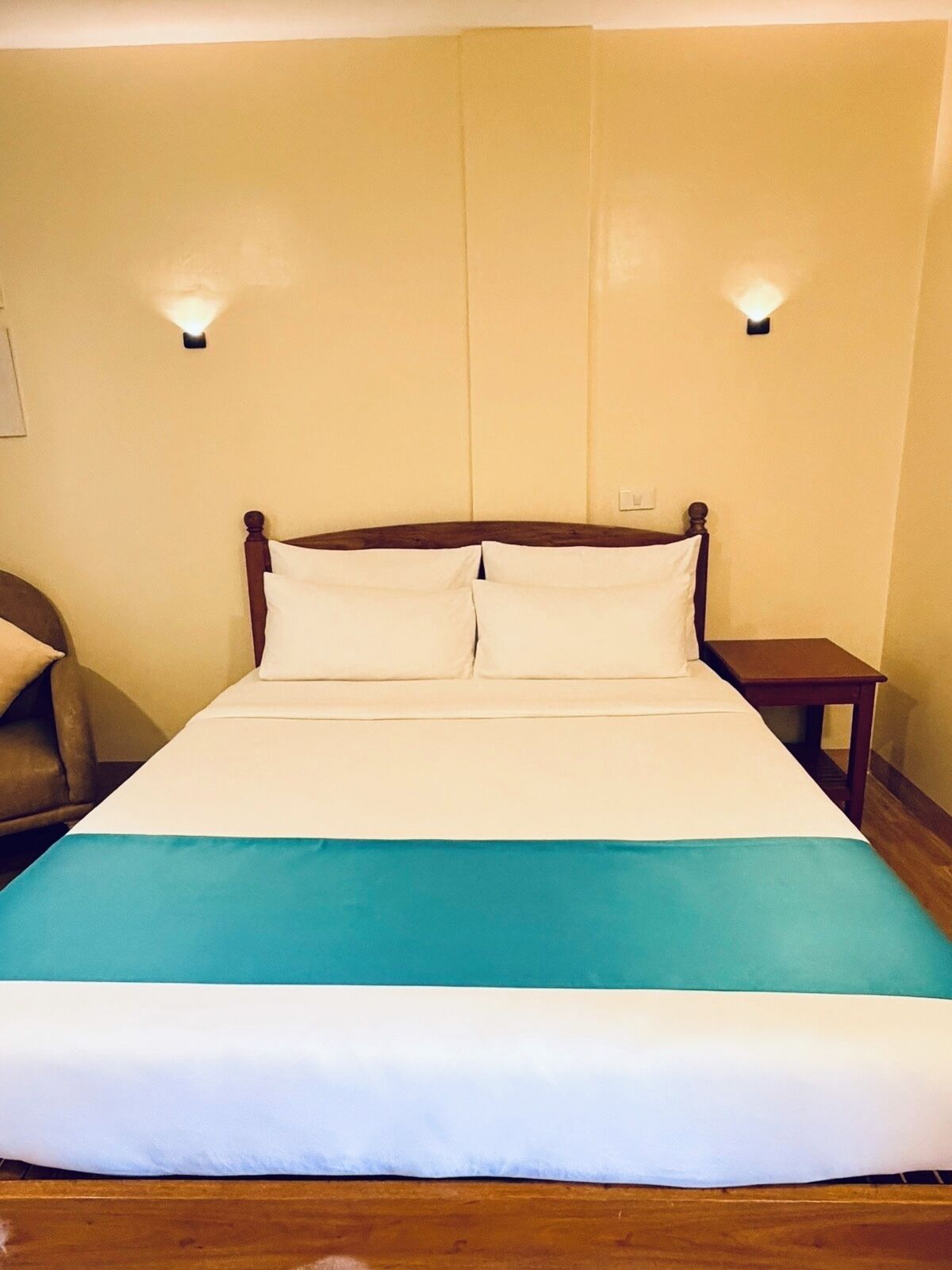 A bed with a wooden headboard, two bedside tables, and a wall-mounted light fixture.