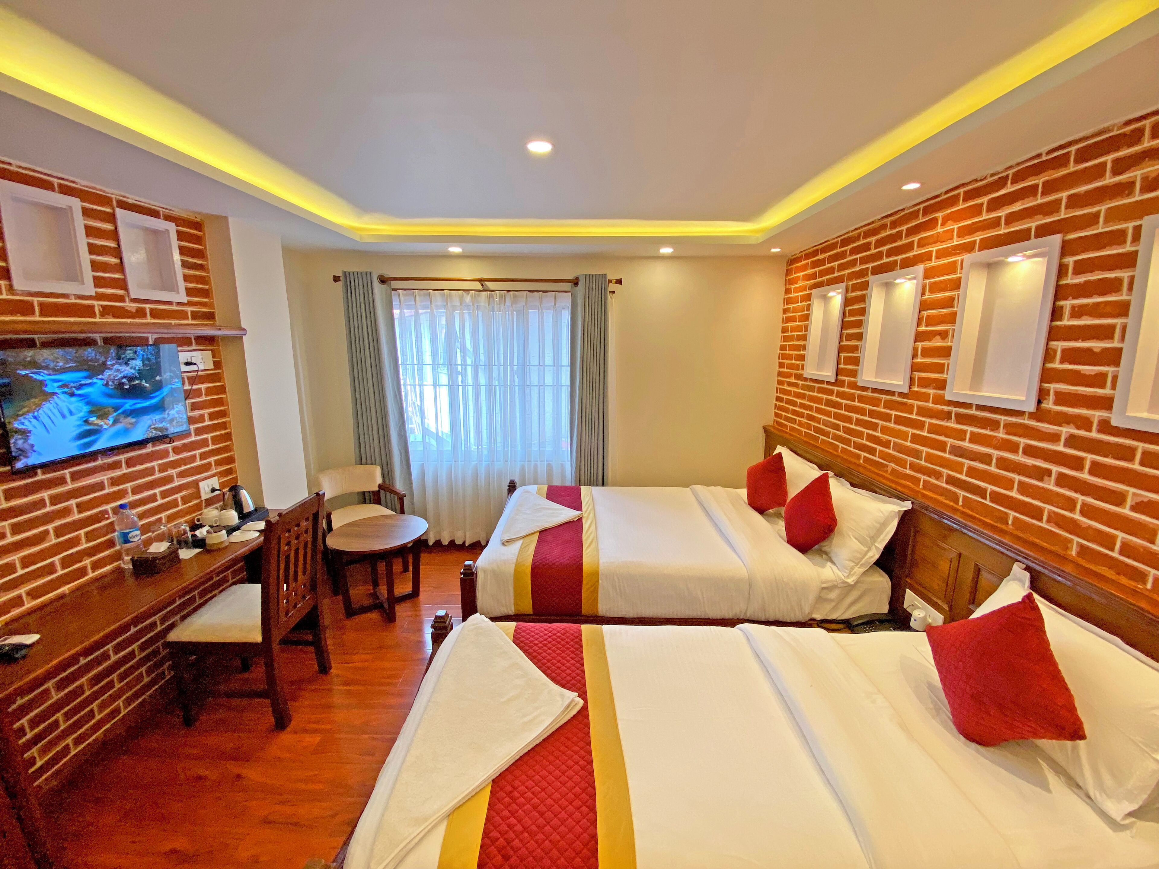 A hotel room with two beds, a TV, a desk, and a chair.