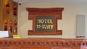 Una mesa de recepción con un cartel que dice "HOTEL SHIVAY" y un calendario.