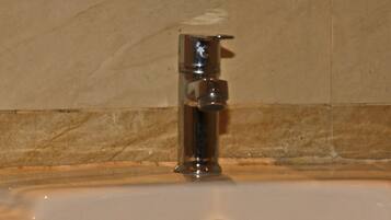 A bathroom sink with a chrome faucet and a visible drain.