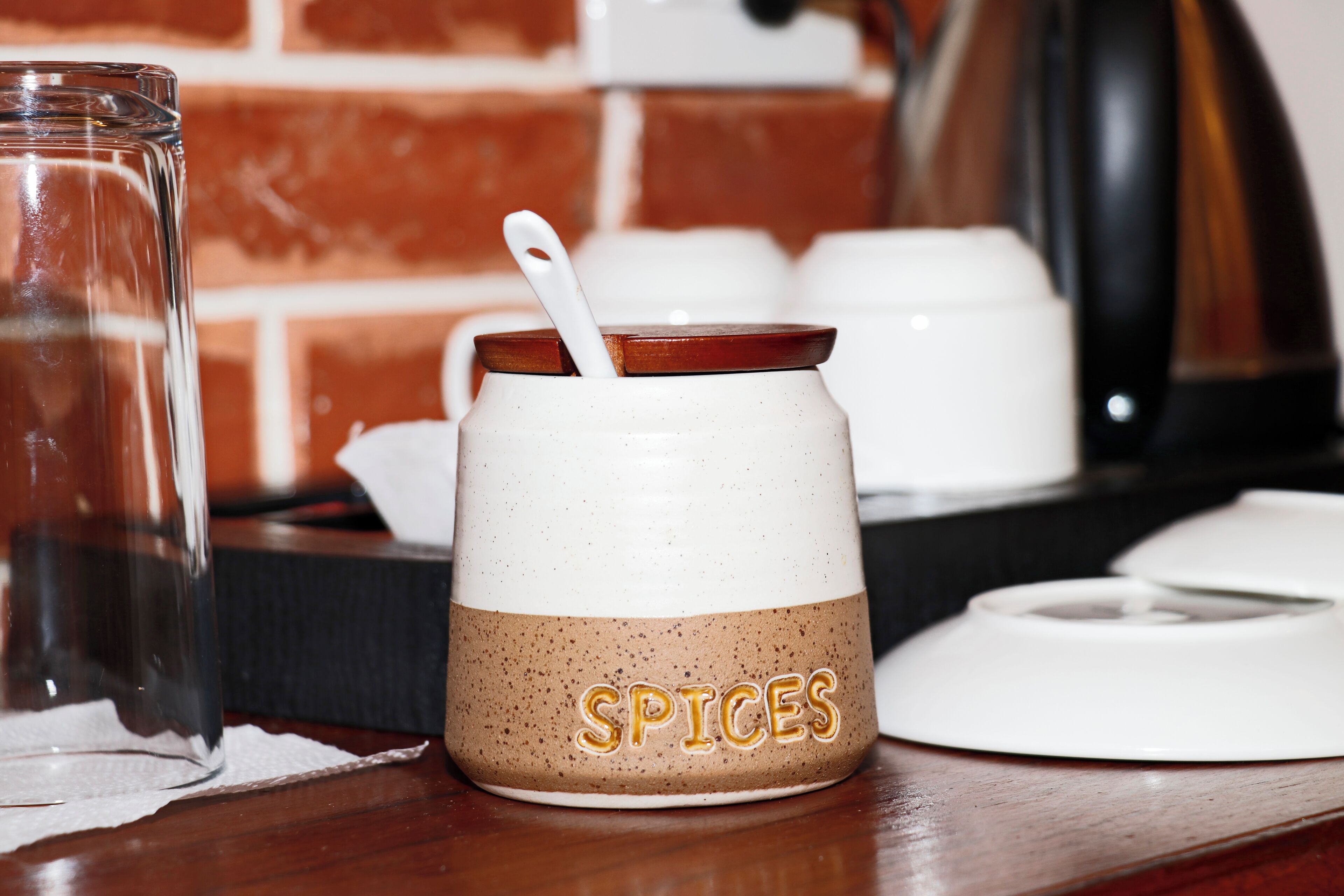 A kitchen counter with a spice jar labeled "SPICES" and a white kettle.