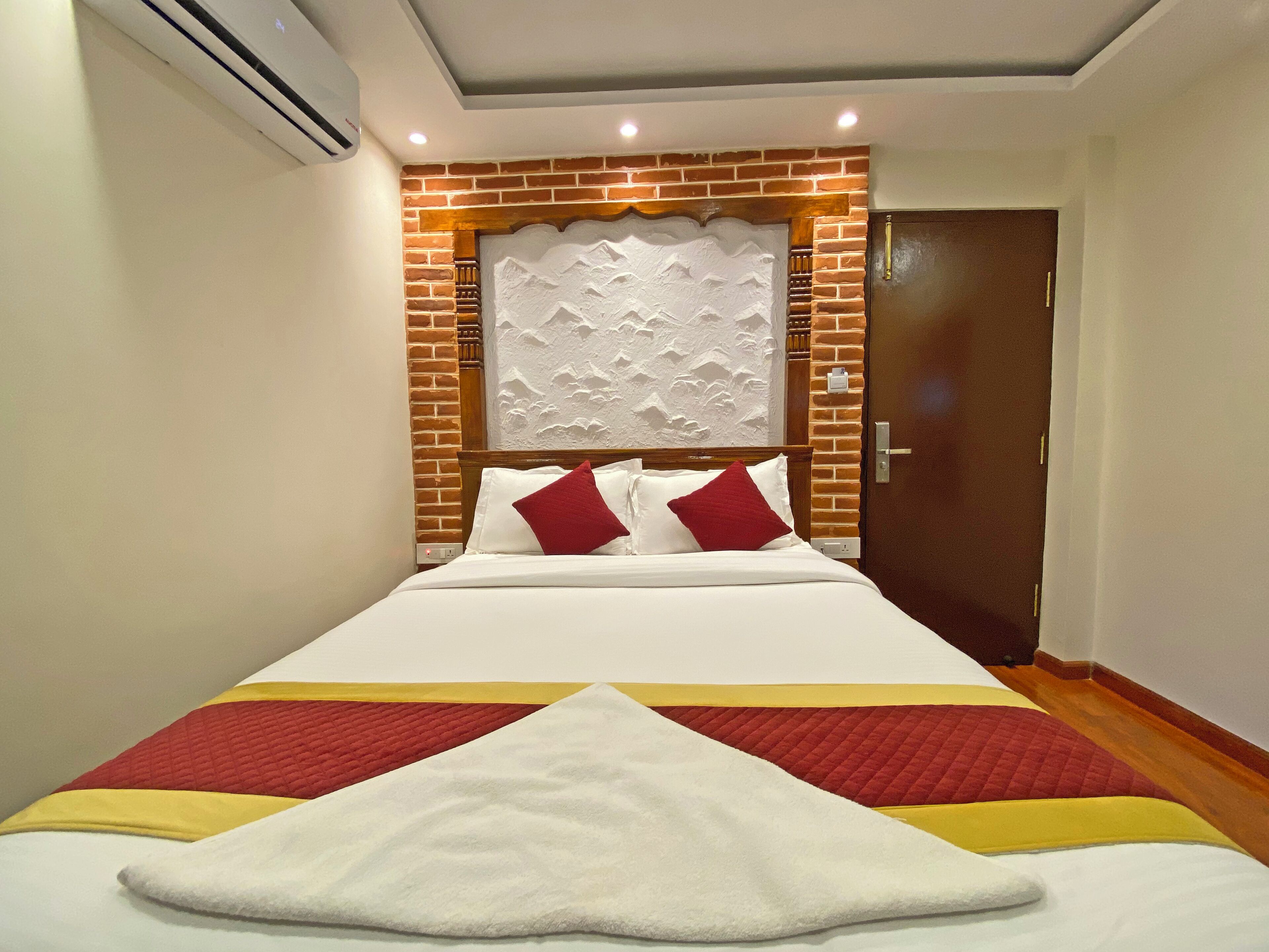 Een hotelkamer met een groot bed, een accentmuur van baksteen en een houten deur.